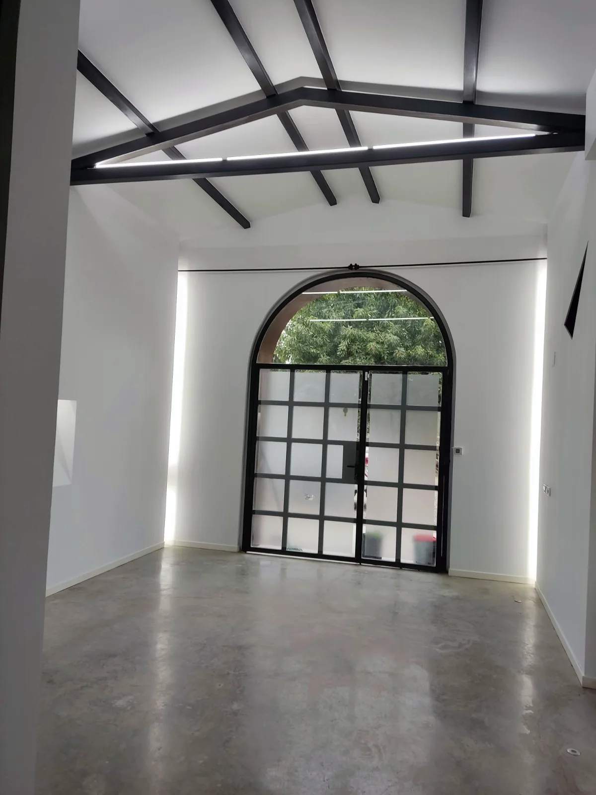 Nave rehabilitada con puerta de arco acristalada y luz LED perimetral