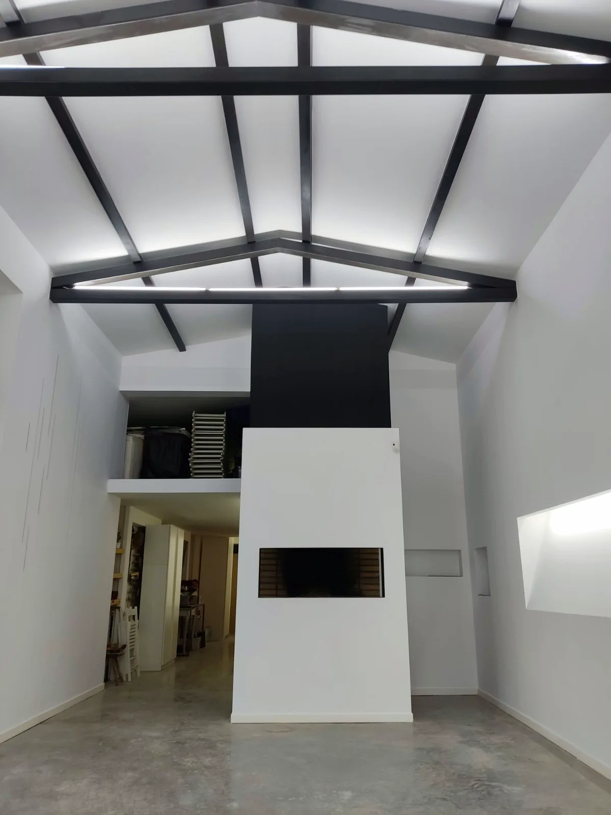Nave rehabilitada con cerchas metálicas negras y chimenea