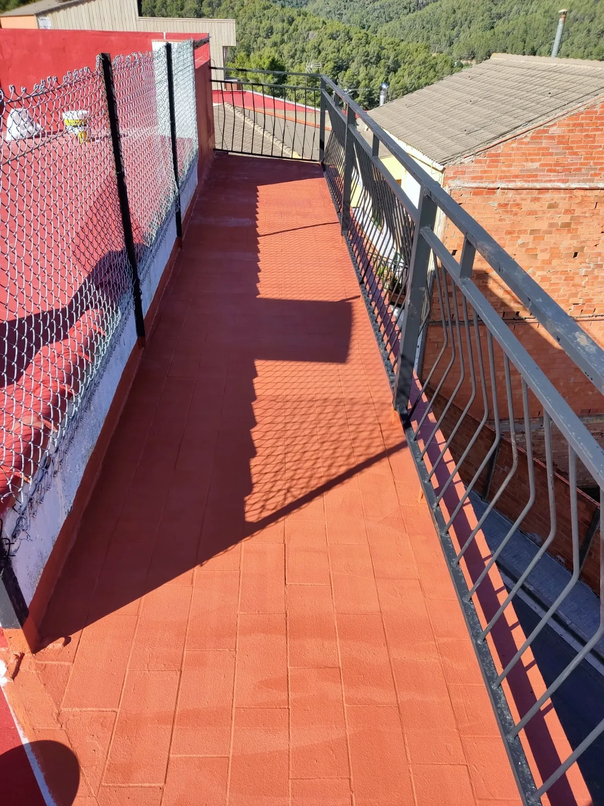 Terraza alargada impermeabilizada en rojo junto a la barandilla